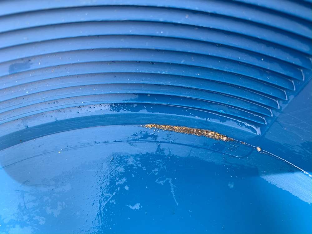 Gold colours and heavy mineral concentrate in the riffles of a blue gold pan